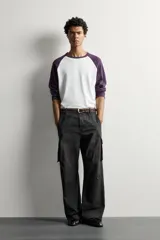 Pantalón cargo de corte relaxed fit, color negro con efecto lavado y estampado de salpicaduras blancas. Cuenta con bolsillos laterales con solapa en las perneras, pinzas en las rodillas y cierre frontal con botón y cremallera.