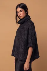 Sweater tipo poncho de tejido de punto grueso en color negro, con cuello alto tipo polera y mangas tres cuartos con puños vueltos.