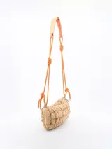 Bandolera de diseño acolchado en color beige, con cierre superior y correa ajustable de cuerda naranja con detalles en negro y refuerzo para el hombro.