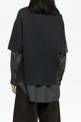 Camiseta negra de corte oversize con cuello redondo y mangas cortas. Presenta un estampado gráfico grande en el frente que simula un paisaje nocturno o crepuscular con un ciervo, árboles y montañas.