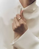 Anillo de oro con diseño envolvente y una perla central incrustada.