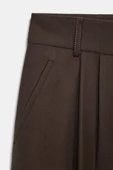 Pantalón de tiro medio confeccionado en mezcla con lana. Presenta diseño de corte recto con detalle de pinzas en el delantero, trabillas en la cintura y bolsillos laterales. Cierre frontal con cremallera, botón y ganchos metálicos.
