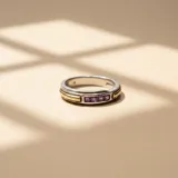 Anillo bicolor de plata y oro con diseño de banda central que incorpora cuatro circonias cuadradas de color violeta engastadas en línea.