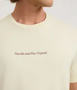 Remera de algodón color amarillo claro, de corte cómodo y manga corta, con cuello redondo y estampa pequeña con la frase "Nascido num País Tropical" en el pecho.