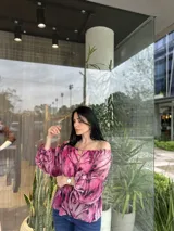 Blusa con hombros descubiertos, estampado floral en tonos rosados y mangas largas abullonadas.