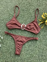 Conjunto de bikini color chocolate con textura acanalada. El corpiño es de estilo triangular con una hebilla metálica decorativa en el centro y breteles finos. La bombacha es de corte colaless con tiras laterales.