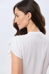 Blusa blanca sin mangas con volados en los hombros, cuello redondo con aberturas y cierre frontal parcial con botones.