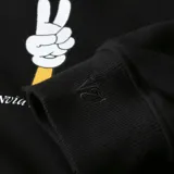 Buzo negro de corte clásico con cuello redondo y puños y cintura acanalados. Estampado pequeño en el pecho de una mano haciendo el signo de la paz.
