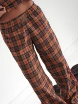 Conjunto de pijama a cuadros con ribetes en color lila, compuesto por camisa de manga larga con botones y pantalón largo.