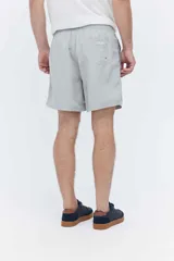 Short de baño oversize gris, con cintura elástica ajustable mediante cordón, bolsillos laterales y detalle de cinta estampada en los laterales.