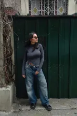 Polera gris de cuello alto, manga larga y corte irregular en el ruedo.