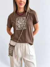 Remera marrón de manga corta y cuello redondo, con estampado floral en un recuadro claro en el frente.