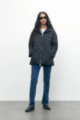 Campera negra con capucha, cierre frontal y diseño capitoneado en forma de rombos.