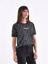 Remera de cuello redondo y manga corta, color negro con estampado integral de estrellas blancas y texto 'STARGIRL' en color amarillo neón en el pecho.