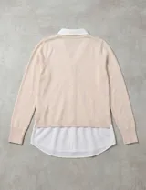 Buzo combinado con torso de tejido de punto fino en color negro y detalles de cuello y ruedo en gasa blanca que simulan una camisa debajo. Presenta escote en V y mangas largas.