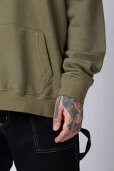Buzo tipo canguro de corte oversize, color blanco, con capucha y cordones ajustables. Presenta un pequeño estampado de una rosa roja en el pecho y un bolsillo frontal tipo canguro.