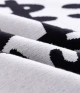 Suéter de corte boxy confeccionado en tejido jacquard de viscosa y poliéster. Presenta cuello redondo, mangas largas y un diseño estampado con lettering en color negro sobre fondo blanco.
