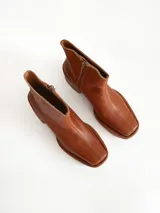 Bota de caña media color óxido, confeccionada en cuero, con plataforma y taco cuadrado texturizado, punta cuadrada y cierre lateral.