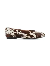 Ballerinas planas confeccionadas en cuero con pelo con estampado animal print de vaca en tonos marrón y blanco, con suela fina y talón cerrado.