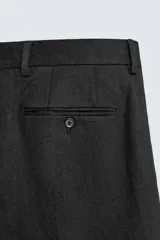 Pantalón de vestir regular fit confeccionado en lino, con pliegues frontales, bolsillos laterales y bolsillos traseros de doble vivo con botón. Presenta cierre frontal con cremallera y gancho metálico oculto.