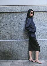 Parka oversize de tejido denim color azul oscuro, con cuello alto, mangas raglán largas, bolsillos laterales, cintura elástica y cierre frontal con botones ocultos.