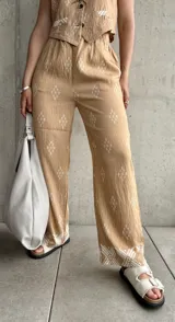 Pantalón beige de corte recto con estampado de rombos blancos y cintura elastizada.