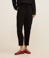 Pantalón de crepé rojo, modelo estilo pijama, de corte fluido, con cintura elástica y lazo de ajuste con terminales metálicas. Cuenta con bolsillos laterales y cierre frontal con cremallera y botón.