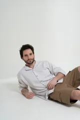 Camisa de manga larga color blanco con finas rayas verticales grises, cuello mao y bolsillo en el pecho.