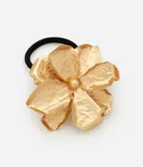 Elástico para el pelo de color negro con un aplique de metal en forma de flor con acabado texturizado y baño dorado claro.