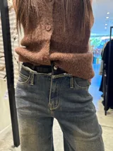 Pantalón de jean de corte ancho y tiro medio, con efecto lavado desgastado en tono azul grisáceo y ruedo desflecado.