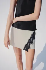 Falda pantalón cruzada de color crudo con detalle de encaje negro a contraste en el delantero y cierre posterior con cremallera oculta.