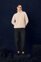 Polera de tejido suave con textura, cuello alto, mangas largas y silueta recta.