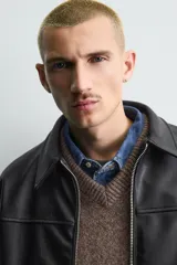 Cazadora bomber de efecto piel color marrón oscuro, con cuello solapa, cierre frontal de cremallera, bolsillos de vivo en cadera y bajo elástico.