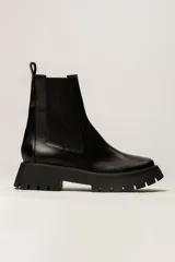 Bota corta negra tipo Chelsea, de cuero liso, con elásticos laterales y suela track gruesa y dentada.