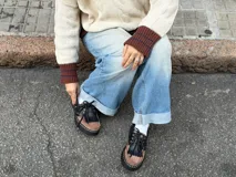 Mocasín de estilo náutico confeccionado en cuero, con diseño bicolor en negro y marrón. Presenta cordones, suela de goma dentada con costuras visibles y detalle de ojales metálicos.