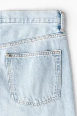 Jean de cinco bolsillos en denim de algodón rígido, de corte holgado con pierna amplia y tiro caído, en color celeste claro con efecto desteñido.
