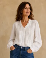 Camisa blanca de manga larga con detalles de encaje, pliegues frontales y cuello con volados.