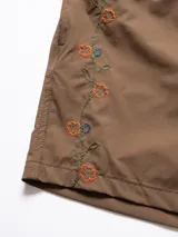 Short de baño azul marino con bordado de enredadera en la pierna izquierda. Tiene cintura elástica con cordón regulable, bolsillos laterales y trasero con cierre, y suspensor de malla fina hipoalergénico.