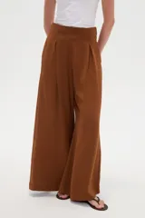 Pantalón ancho de poliéster color marrón, de tiro alto con pinzas en la cintura y punto smock en la parte posterior.