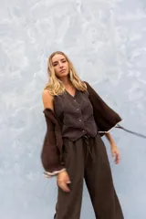Chaleco negro de pana fina, con escote en V y cierre frontal de botones. Presenta un diseño entallado con corte en la cintura.