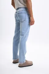 Pantalón de jean clásico color azul claro, con corte recto y tiro medio. Presenta bolsillos delanteros y traseros, y cierre de botón y cremallera.
