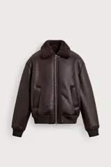 Cazadora oversize color marrón de efecto piel, con interior de pelo sintético a contraste. Cuenta con cuello solapa, manga larga, bolsillos de vivo en la cadera, acabados en rib y cierre frontal con cremallera.