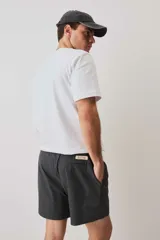 Short de baño color gris oscuro, con cintura elástica ajustable mediante cordones blancos y un pequeño parche decorativo en el borde inferior.