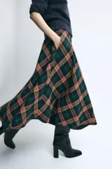 Falda midi de tiro medio, evasé, confeccionada con mezcla de viscosa y diseño de cuadros en tonos verdes, marrones y negros. Cuenta con cierre de cremallera oculta en la costura.