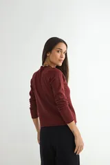 Sweater de punto negro con cuello redondo y detalle de borde ondulado, de manga larga y corte clásico.