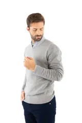 Sweater de punto con escote en V y mangas largas, confeccionado en una mezcla de algodón, nylon y spandex. Presenta un diseño clásico de corte recto con puños y ruedo acanalados.