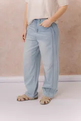 Jean de calce relajado y pierna amplia color beige, con tiro alto y detalle de recortes y costuras visibles.