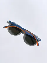 Lentes de sol Osten modelo Maui, con armazón negro de diseño redondeado y detalles en color naranja en las patillas. Cuentan con cristales polarizados con protección UV 400.