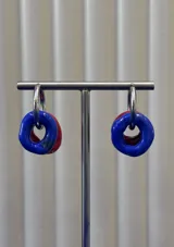 Aros tipo argolla de plata 925 con dijes circulares de vidrio en colores azul y rojo.