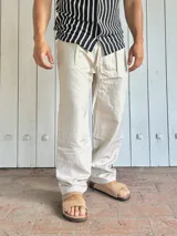 Pantalón de lino color beige, de corte ancho y relajado, con cintura ajustable mediante cordón.